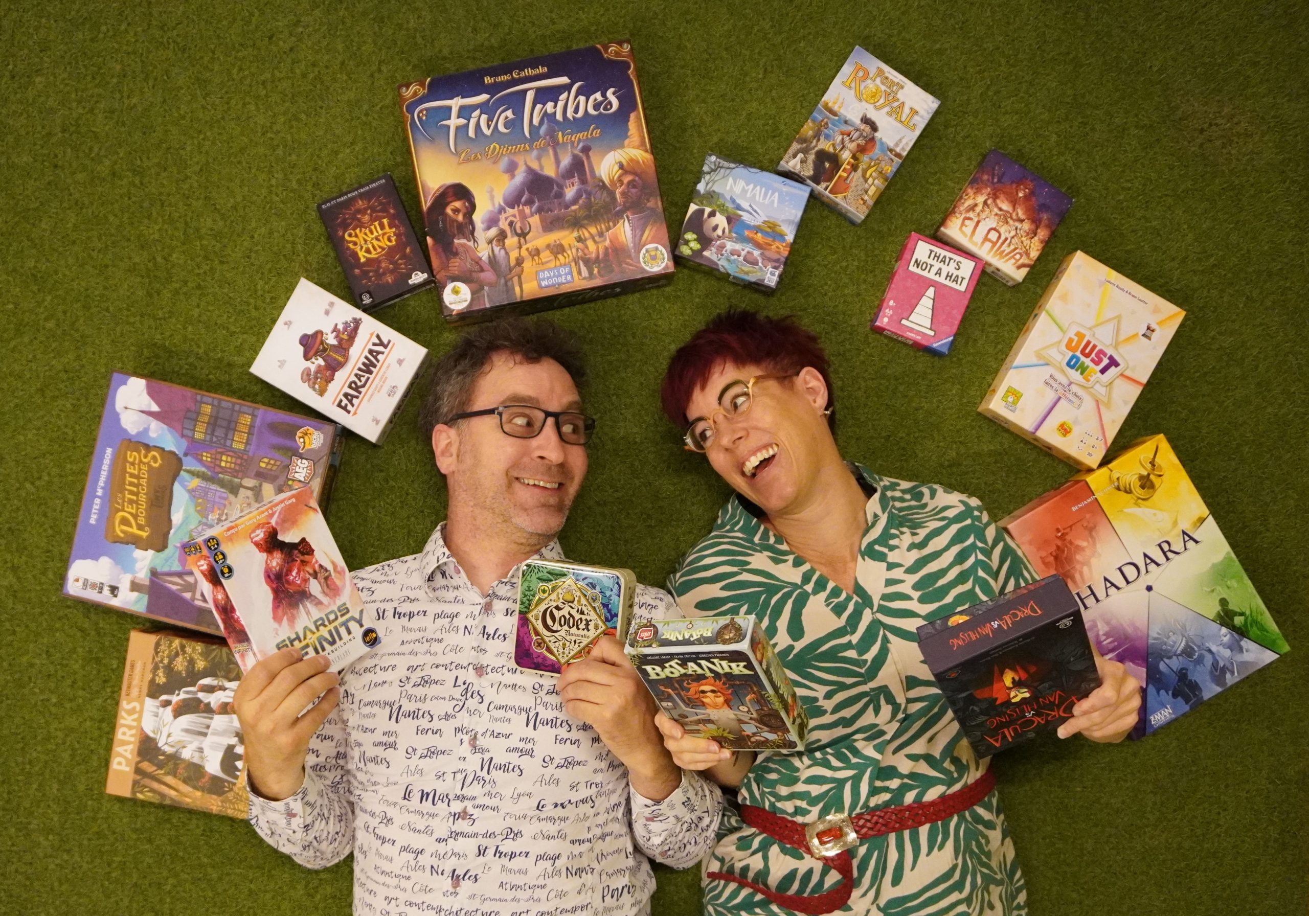 Eric et Mélanie sont couchés sur un tapis vert et sont entourés de jeux de société
